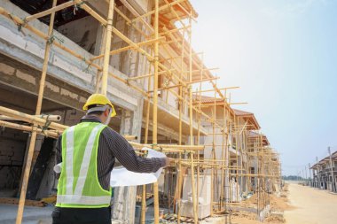 İnşaat alanının arka planında koruyucu mimar ve bina planları olan profesyonel mühendis.