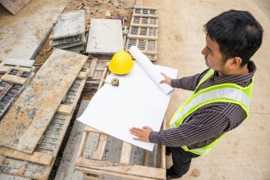 Genç iş adamı profesyonel mühendis bina inşaatında proje üzerinde çalışıyor.