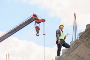 İş adamı mühendis koruyucu miğfer ve inşaat alanındaki planlar üzerinde çalışıyor.
