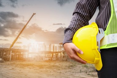 Asyalı işadamı inşaat mühendisi koruyucu miğfer ve bina inşaatında kullanılacak planlar.