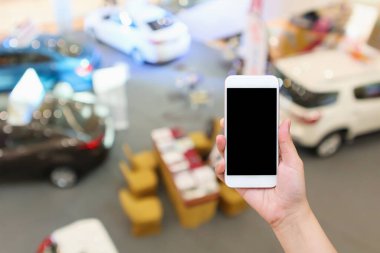 Soyut bulanık araba galerisi üst görünümü olan el kameralı akıllı telefon.