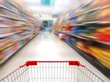 Süpermarket rafları arka planı bulanıklaştırıyor ve alışveriş arabası hareket ediyor