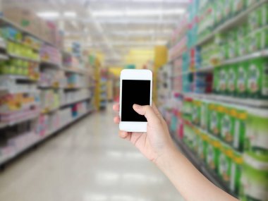 Süpermarket rafları ile el ele tutuşan cep telefonu koridoru bulanık