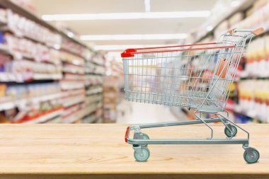 Market alışveriş arabası ahşap sehpanın üzerinde. Bakkal koridoru bulanık.