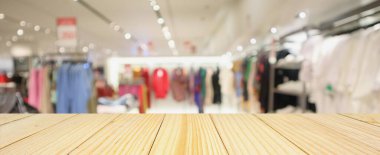 Boş ahşap masa ve alışveriş merkezindeki şık butik giyim mağazası vitrinleri.