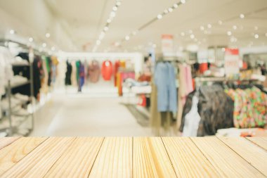 Boş ahşap masa ve alışveriş merkezindeki şık butik giyim mağazası vitrinleri.