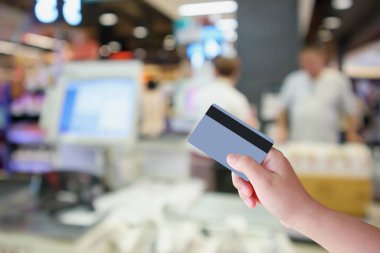 Süpermarket kasiyeriyle el ele tutuşan kredi kartı. Müşteri odaklı olmayan arka plan, alışveriş ve ödeme konsepti.