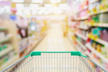 Yeşil alışveriş arabasının arka planı bulanık süpermarket koridoru