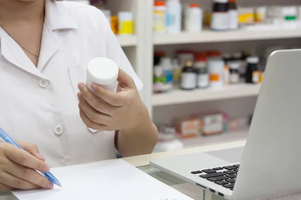 Pharmacist with laptop computer and medication in the pharmacy store