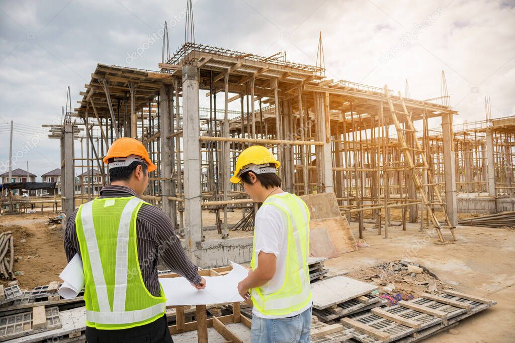 Asian business man construction manager and engineer worker in protective helmet hold blueprints paper on hand at house building site