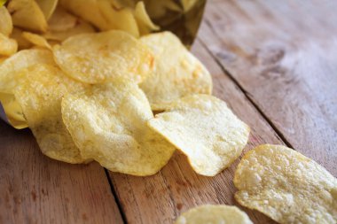 Ahşap masada bir paket lezzetli patates cipsi.