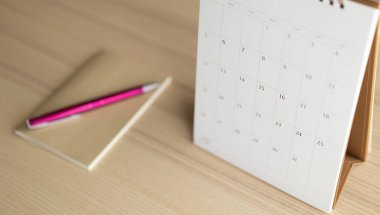 Takvim sayfası ahşap masa arkaplanını kalem ve defter iş randevusu planlama konseptiyle kapat