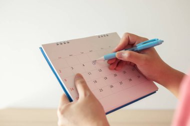 Takvimde 5. sırada mavi daireli kalem izi olan el.