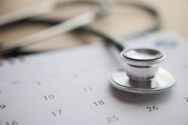 Ahşap masa arkası doktor randevu konseptinde takvim tarihli steteskop