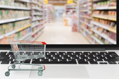 Bilgisayarda boş süpermarket arabası ve ekranda bulanık market çevrimiçi alışveriş kavramı