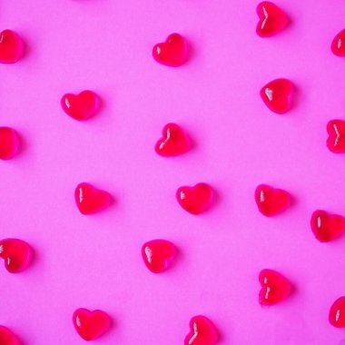 Sevgililer Günü geçmişi, pembe arka planda kalp şeklinde şekerler.