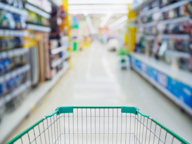 Boş yeşil alışveriş arabasıyla dolu süpermarket koridoru bulanık arka plan