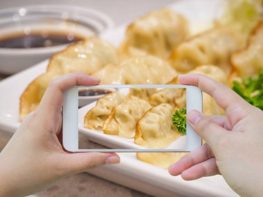 akıllı telefonlu Gyoza hamur köftelerinin fotoğrafını çekiyor.