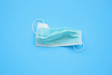 Mavi arka planda COVID-19 Coronavirus 'a karşı tek kullanımlık cerrahi maske. Sağlık ve Tıp Konsepti