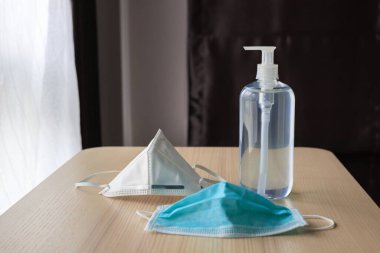 Covid-19 Coronavirus önleme konsepti için ahşap masaya alkol dezenfektanlı yüz maskesi.