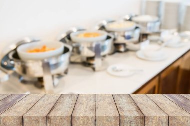 Ahşap masa ve otel restoranının arka planındaki ısıtmalı tepsiler ürün gösterimi için bulanık.