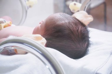 Yeni doğmuş bebek doğum odasındaki kuvözün içinde.
