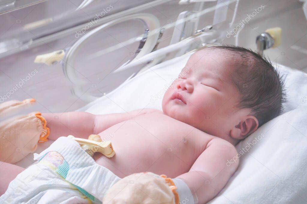 Newborn baby girl inside incubator in hospital post delivery room