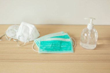 Covid-19 Coronavirus önleme konsepti için ahşap masaya alkol dezenfektanlı yüz maskesi.