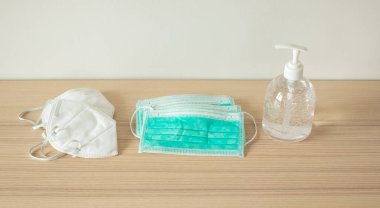 Covid-19 Coronavirus önleme konsepti için ahşap masaya alkol dezenfektanlı yüz maskesi.