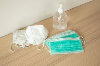 Covid-19 Coronavirus önleme konsepti için ahşap masaya alkol dezenfektanlı yüz maskesi.