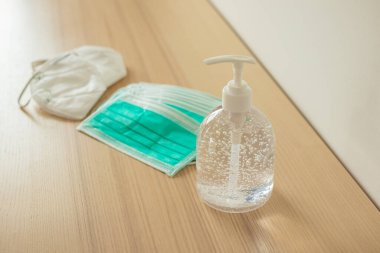 Covid-19 Coronavirus önleme konsepti için ahşap masaya alkol dezenfektanlı yüz maskesi.