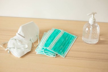 Covid-19 Coronavirus önleme konsepti için ahşap masaya alkol dezenfektanlı yüz maskesi.