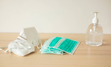 Covid-19 Coronavirus önleme konsepti için ahşap masaya alkol dezenfektanlı yüz maskesi.