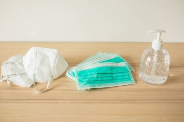 Covid-19 Coronavirus önleme konsepti için ahşap masaya alkol dezenfektanlı yüz maskesi.