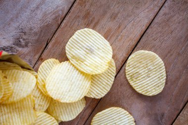 Tahta masanın üzerinde patates cipsi ile açılmış paket.