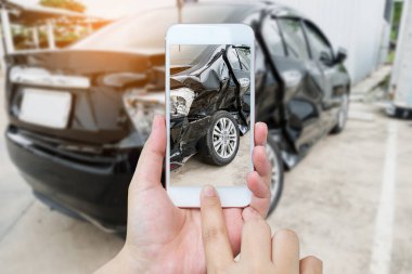 Kadın cep telefonuyla sigorta için araba kazası fotoğrafı çekiyor.