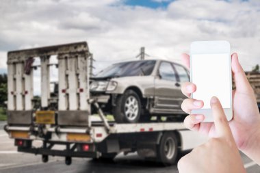 El, trafik kazasından sonra çekçekilen aracın yanında acil yol servisi için cep telefonu kullanıyor.