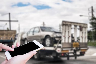 El, trafik kazasından sonra çekçekilen aracın yanında acil yol servisi için cep telefonu kullanıyor.