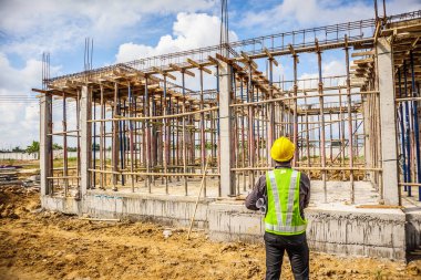 Asyalı işadamı inşaat mühendisi koruyucu miğfer ve bina inşaatında kullanılacak planlar.