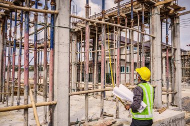 Asyalı işadamı inşaat mühendisi koruyucu miğfer ve bina inşaatında kullanılacak planlar.