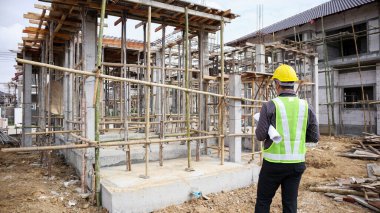 Asyalı işadamı inşaat mühendisi koruyucu miğfer ve bina inşaatında kullanılacak planlar.