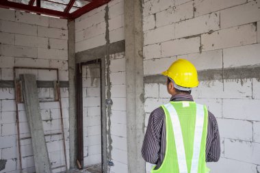 Asyalı işadamı inşaat mühendisi koruyucu miğfer ve bina inşaatında kullanılacak planlar.