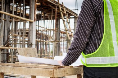 Genç iş adamı profesyonel mühendis bina inşaatında proje üzerinde çalışıyor.