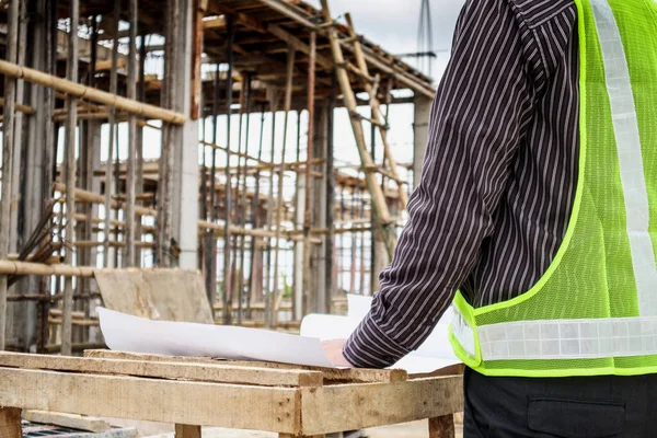 Genç iş adamı profesyonel mühendis bina inşaatında proje üzerinde çalışıyor.