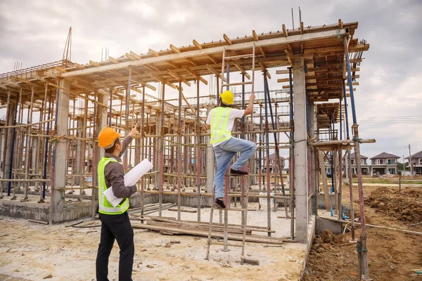 亚洲商人 建筑经理和戴防护头盔的工程师在建筑工地拿着设计图纸 — 图库照片