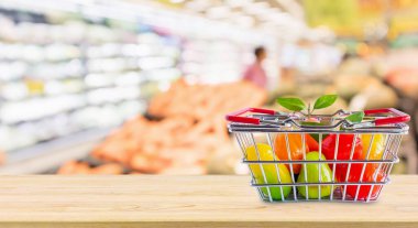 Marketin arka planında, ahşap masada meyveli alışveriş sepeti.