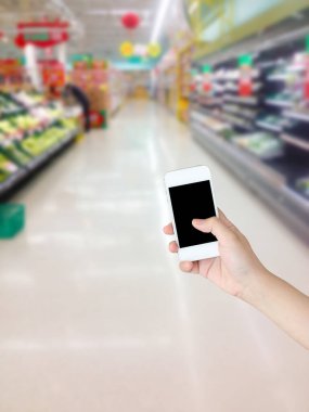Sebzeli cep telefonu ve markette rafta duran meyve bulanık arka plan.
