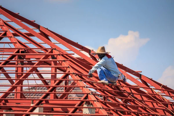 在有云彩和天空的建筑工地安装房屋屋顶钢架结构的建筑工人 — 图库照片