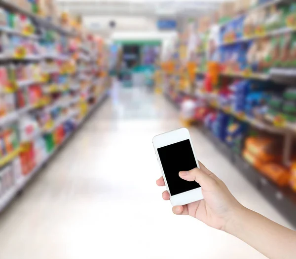 Mão Segurando Telefone Celular Com Prateleiras Supermercado Corredor Desfocado Fundo — Fotografia de Stock