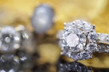 Şatafatlı altın mücevher yüzükler siyah arka planda yansıyor.